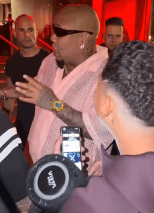 Bulin 47 freestyling outside a red-lit restaurant entrance while Kevin Wai holds a portable speaker, October 2026